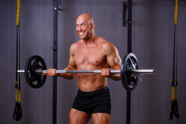 Genç sağlıklı kel sökük gülümseyen adam tutarak büyük kaslı bir