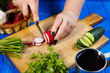  Eller kadın kesme taze gevrek turp ile kesme tahtası üzerinde 