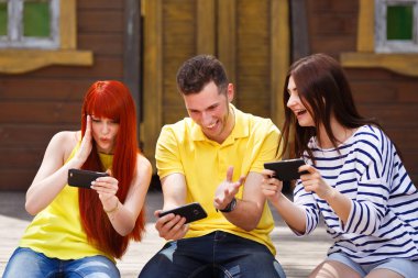 Grup üç arkadaş oyun mobil video oyunu açık havada, kız ve