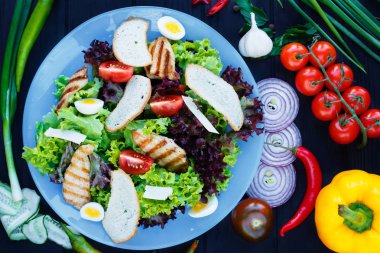 Sezar salatası ile süslenmiş mavi plaka üzerinde ızgara tavuk 