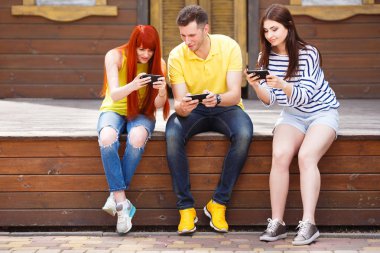 Üç genç arkadaş izlerken gülmekten video cep telefonu outd
