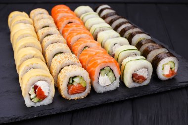 Lezzetli taze çok renkli suşi siyah arduvaz ayarla yakın çekim.