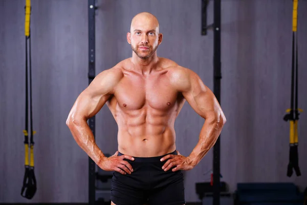 Jovem careca saudável rasgado homem com grandes músculos posando no ginásio — Fotografia de Stock