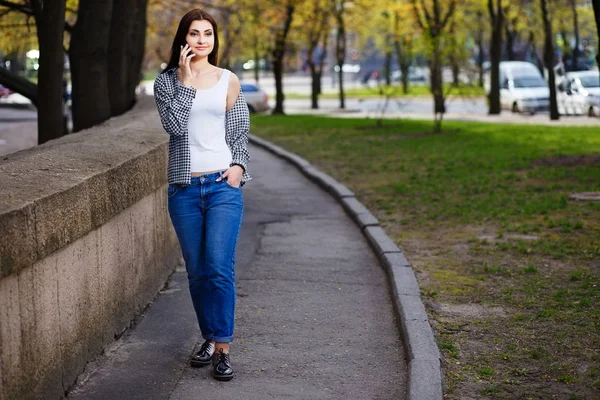 Jeune femme assez élégante parlant sur le téléphone intelligent dans la rue — Photo