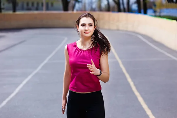 Junge, fitte Frau joggt auf dem Sportplatz — Stockfoto