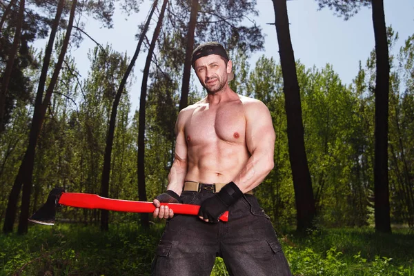 Lumberjack arbetare står i skogen med yxa — Stockfoto