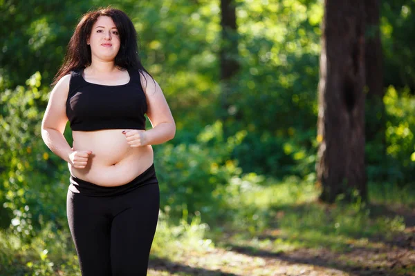 Młoda kobieta nadwagą jogging w parku — Zdjęcie stockowe