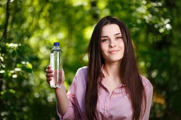 Feliz hermosa joven sonriente mujer sosteniendo una botella de wa limpio — Foto de Stock
