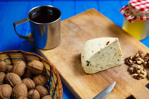 Кусок домашнего острого сыра с грецкими орехами, кружка домашнего вина — стоковое фото