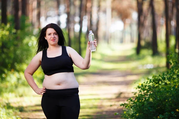 Young overweight smiling woman with a bottle of clear water outd — Stock Photo, Image