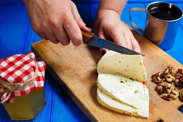 Жінка руками ріже гострий домашній сир на обробній дошці, подавати — стокове фото