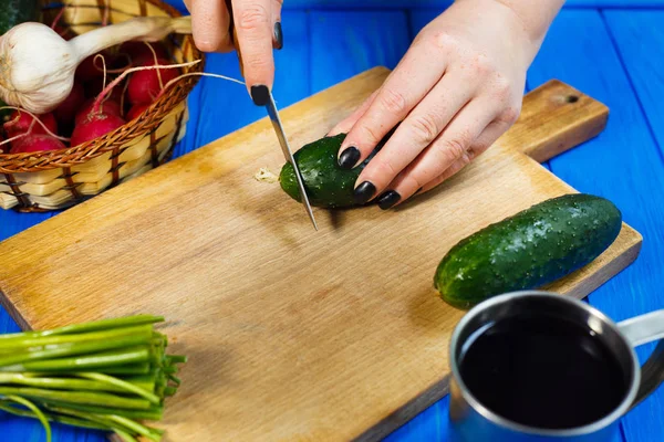 Las manos de la mujer cortando pepino crujiente fresco en la tabla de cortar con — Foto de Stock