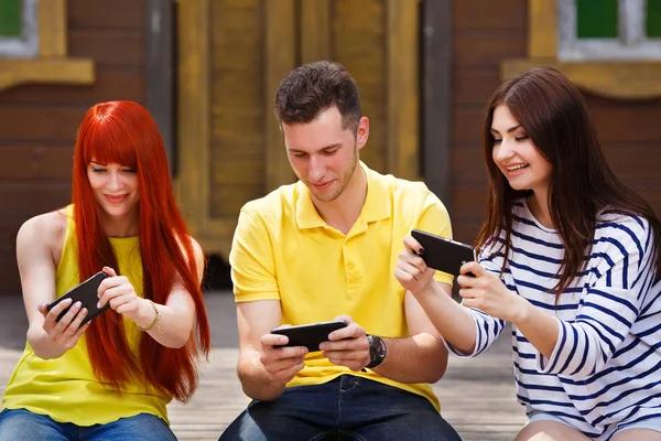 Group of youth laughing playing mobile video game outdoors