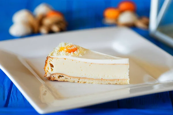 Üzerinde kumquats ve badem ile kare plaka üzerinde peynir pasta dilimlenmiş — Stok fotoğraf