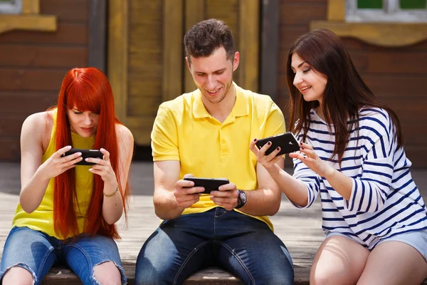 Group of youth laughing playing mobile video game outdoors