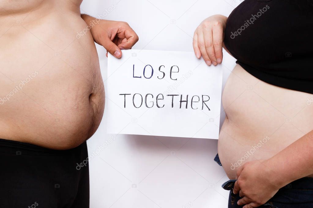 Close-up portrait of man and woman obese bellies and hands holdi