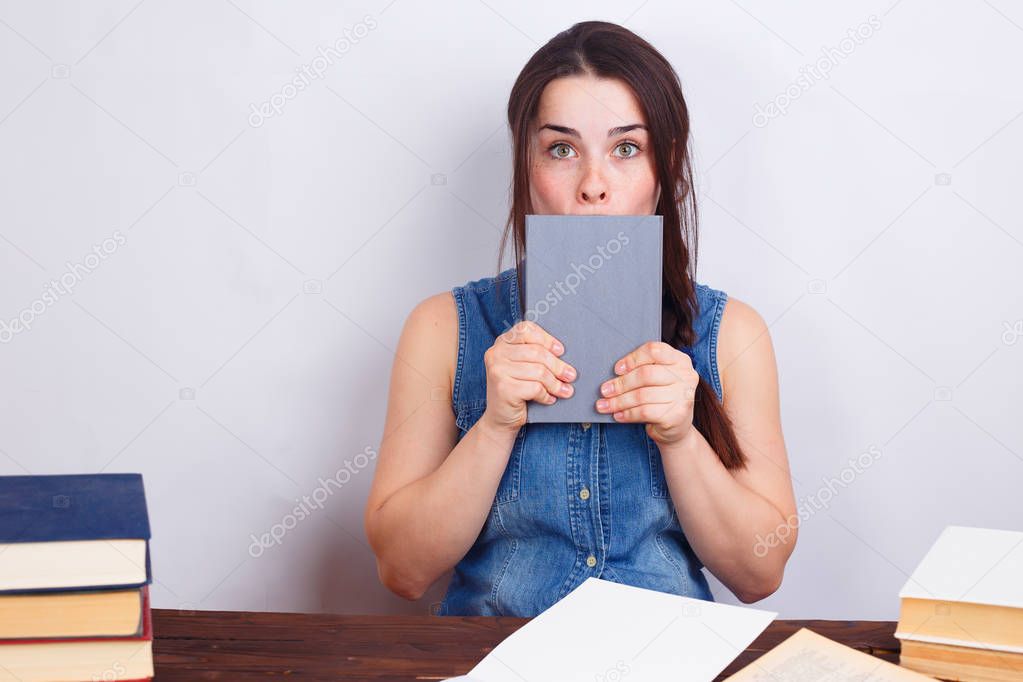 Portrait of young surprised shocked student woman with a book in