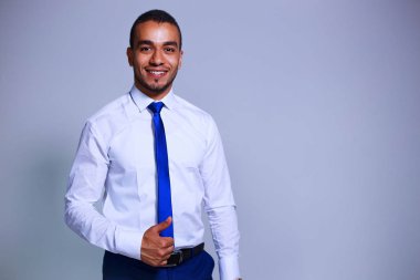 Gri arka plan üzerinde duran kendine güvenen genç işadamı portresi. İş, insan ve office kavramı