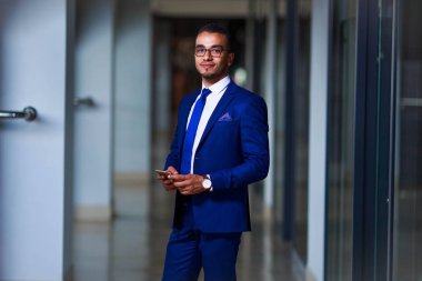 Kendine güvenen genç iş adamı takım elbise ve ayakta gözlük 