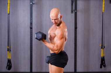 Güçlü kel adam spor salonunda dumbbells ile çalışma dışarı sökük. Spor,