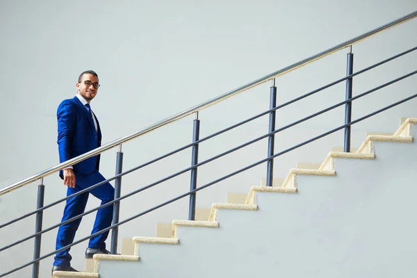 Stairs to success. Young smiling businessman climbs the stairs