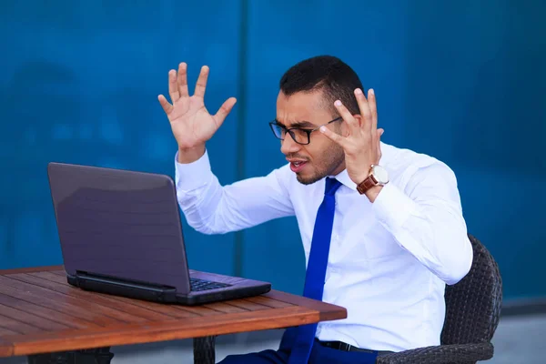 Stressé jeune homme d'affaires en colère avec ordinateur portable assis à la table - — Photo