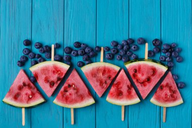 Mavi ahşap arka yüzündeki bir yaban mersini ve karpuz dilimi popslices