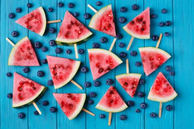 Mavi ahşap arka yüzündeki bir yaban mersini ve karpuz dilimi popslices
