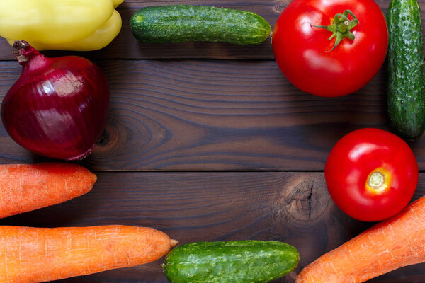 Fresh organic vegetables frame on wooden background, free space.