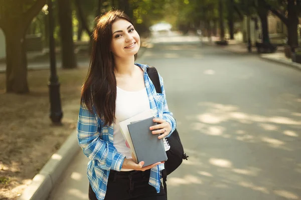 Sırt çantası ve kitaplar arasında olan genç sevimli gülümseyen öğrenci kadın — Stok fotoğraf