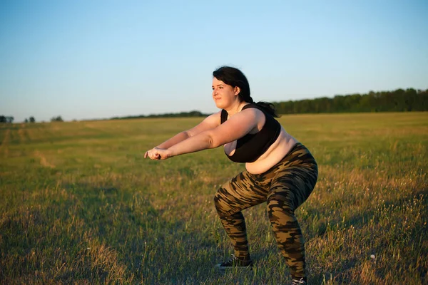 Overweight fat woman squats in the meadow on the grass. Weight l — Stock Photo, Image