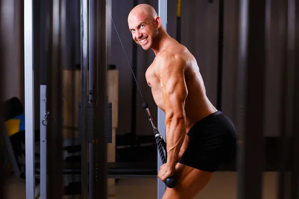 Un uomo forte e calvo che pompa ferro. Uomo sportivo bodybuilder smil — Foto Stock