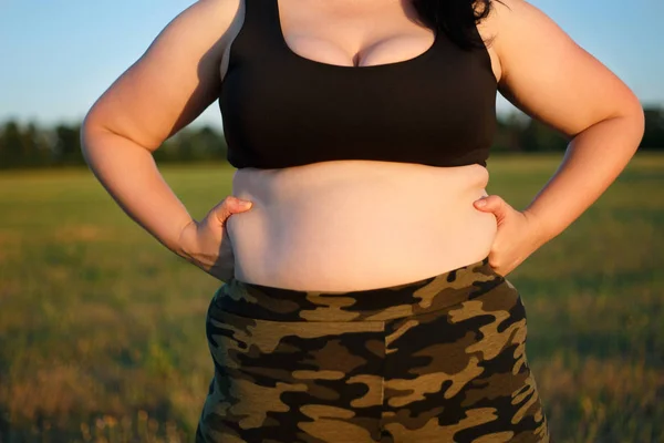 Överviktig fet kvinna i kamouflage byxor stående utomhus kvadraterna — Stockfoto