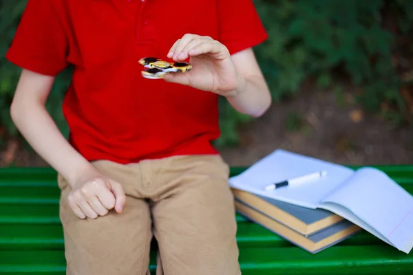 Adicción a los artilugios. Colegial jugando con fidget spinner en su lugar —  Fotos de Stock