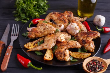 Sarımsak ve s ile dekore edilmiş siyah plaka üzerinde ızgara tavuk kanatları