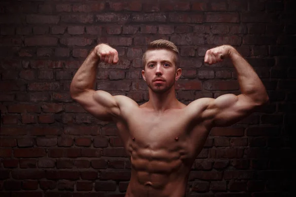 Young fit man bodybuilder with perfect big muscles posing over b — Stock Photo, Image
