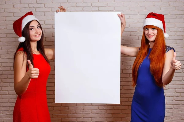 Two beautiful smiling women in Santa caps with thumb up gesture — Stock Photo, Image