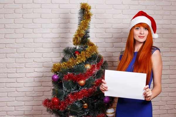 Young beautiful redhead woman in Santa cap holding an empty boar — Stock Photo, Image