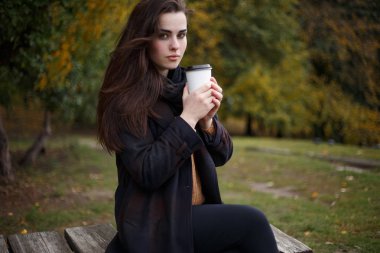 Tortum içinde oturan şık kareli ceket giyen genç kadın