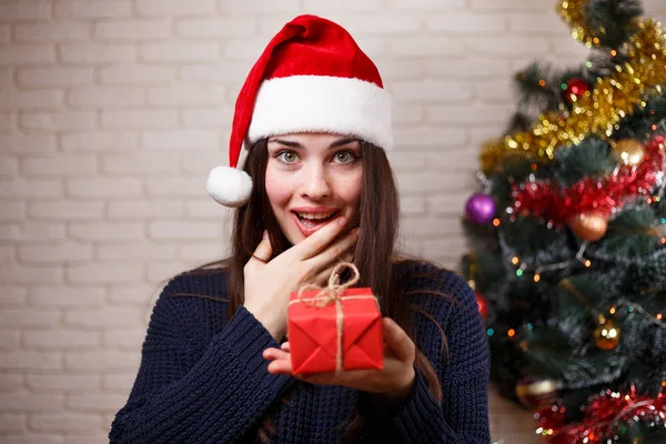 Young cute surprised woman in Santa cap is surprised to get a pr — Stock Photo, Image