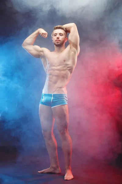 Young fit man bodybuilder with perfect big muscles over smoky ba — Stock Photo, Image