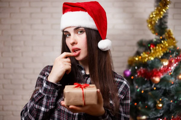 Young cute sexy woman in Santa cap guessing a gift on christmas — Stock Photo, Image