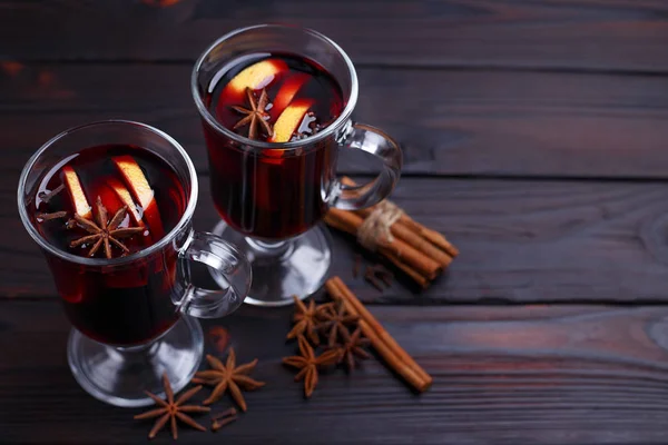 Glühwein, Zimtstangen und Anis auf dunklem Holzgrund — Stockfoto