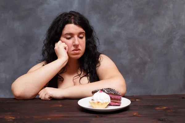 Young upset overweight woman bored of diets looking on sweets, c — Stock Photo, Image