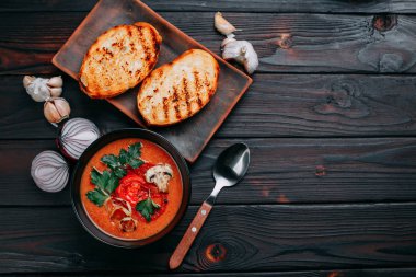 Dilimlenmiş petrol ve domates ile dekore edilmiş kremalı domates çorbası