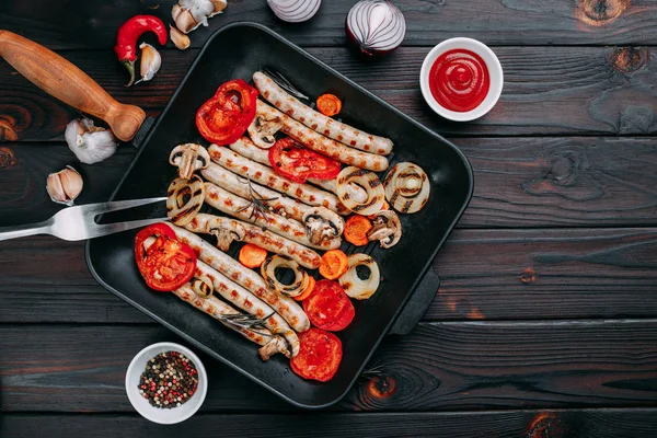 Grillade korvar och grönsaker serveras i en grillpanna med sås — Stockfoto