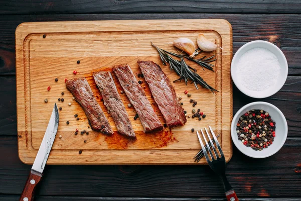 Sliced well-done grilled steak on wooden cutting board with rose — Stock Photo, Image