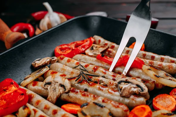 Processo de cozinhar salsichas grelhadas apetitosas e legumes em — Fotografia de Stock