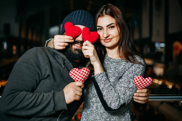 Jovem mulher cobrindo seus namorados olhos com vermelho travesseiro corações — Fotografia de Stock