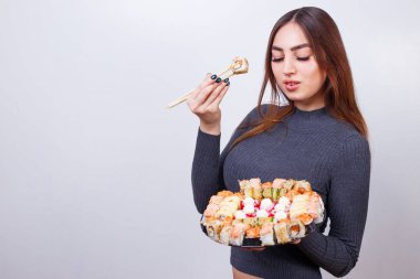 Genç güzel kadın yemek suşi, stüdyo ateş üzerinde beyaz backgr
